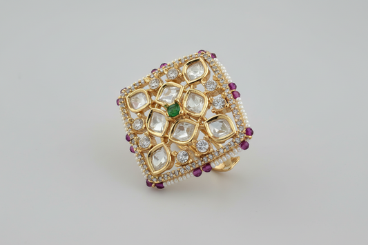 Gold plated ring with gemstones on a light gray background