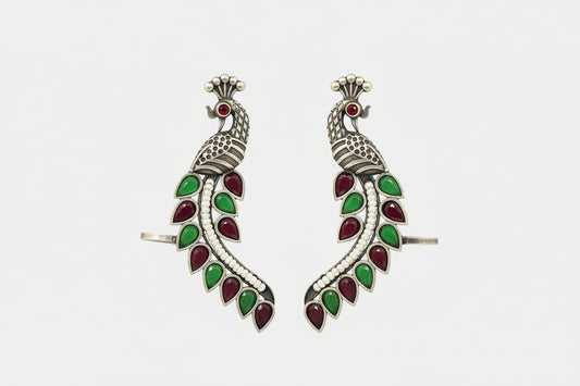 Pair of silver earrings with green and red gemstones on a green background