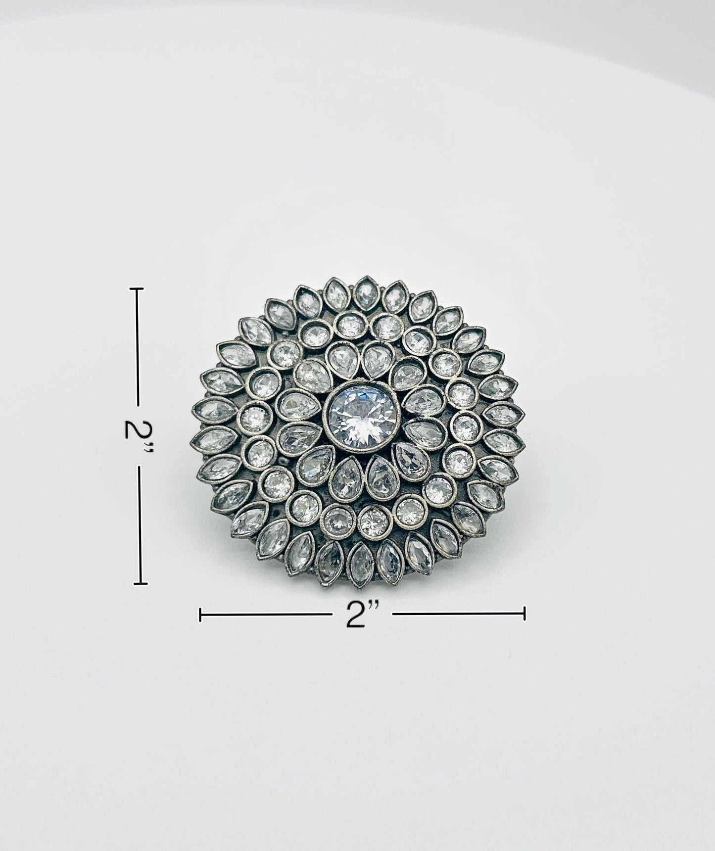 Decorative brooch with gemstones on a white background, shown with measurements.
