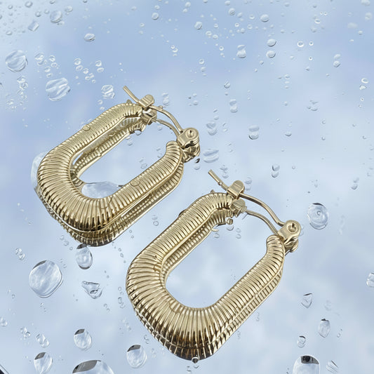 Gold hoop earrings on a water droplet background