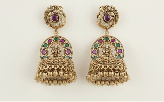 temple gold plated earrings with ruby red and green gemstones on a being background