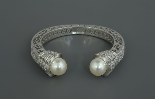 Silver kada with pearl-like beads on a red background