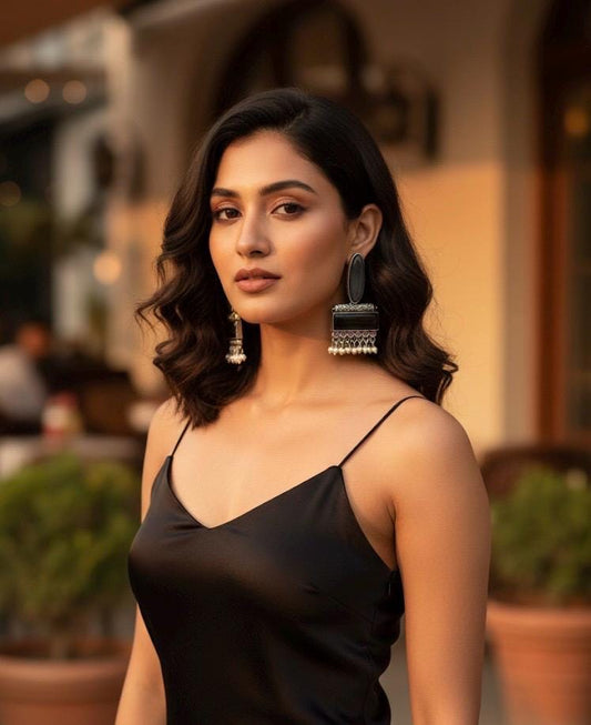 Woman wearing a black dress with large earrings in an outdoor setting