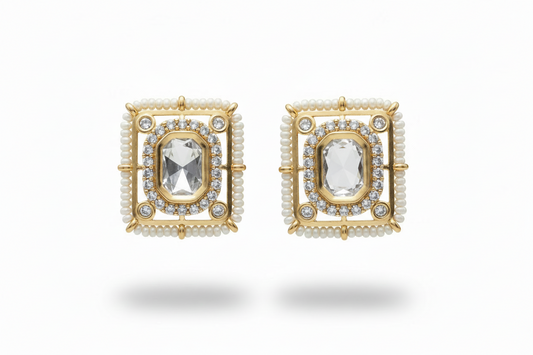 Pair of kundan gold plated earrings with central gemstones on a white background
