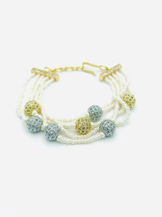 Multistrand pearl bracelet with gold and silver beads on a white background