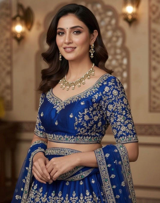 Woman wearing a blue embroidered traditional outfit with jewelry indoors.
