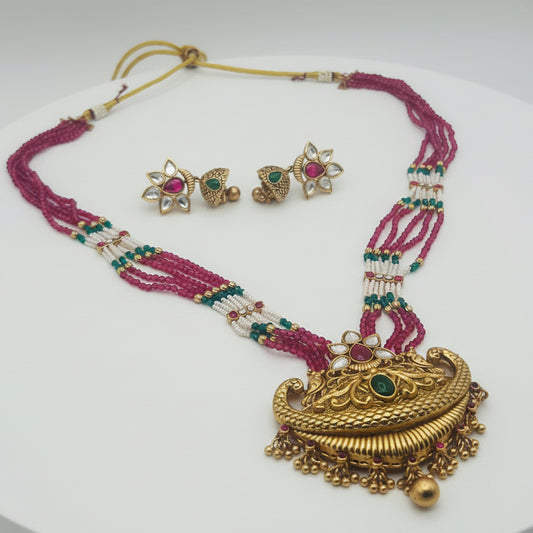 Gold necklace with pink beads and matching earrings on a white background
