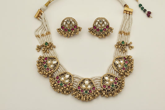 Jewelry set including a necklace, and earrings on a white plate with a gray background