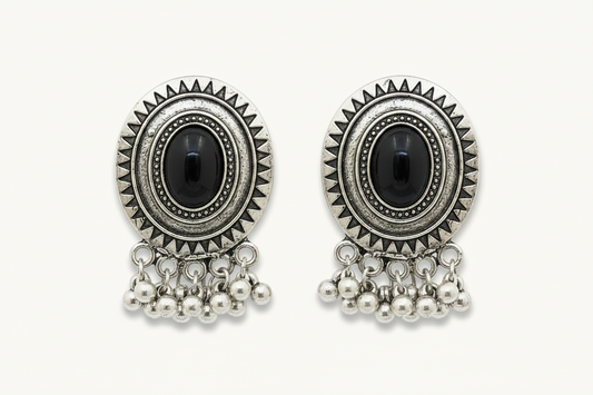 Pair of silver earrings with black gemstones and pearl-like beads on a white background