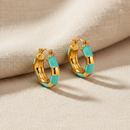 Gold hoop earrings with turquoise accents on a beige fabric background