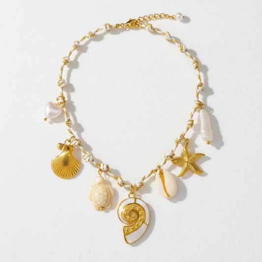18k Gold plated and white beaded necklace with shell, turtle, and starfish charms on a light gray background