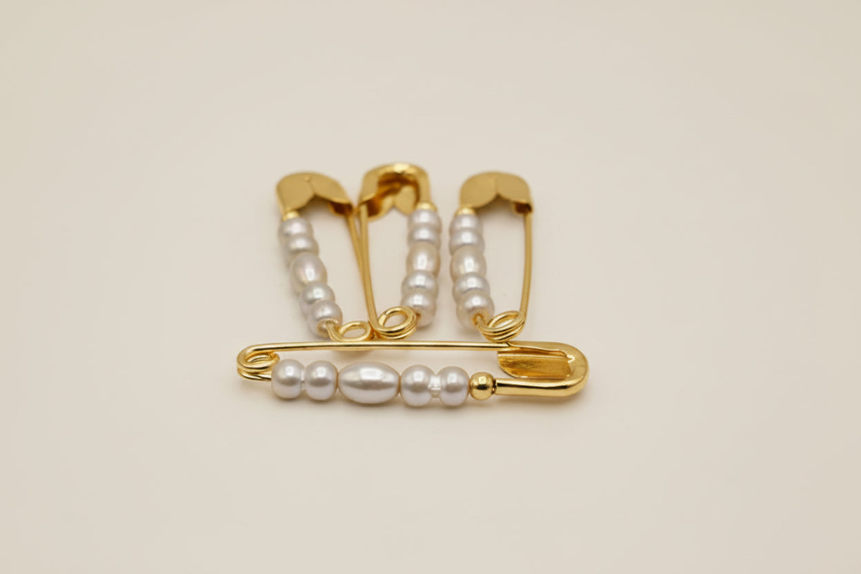 safty pins with pearls on a light gray background