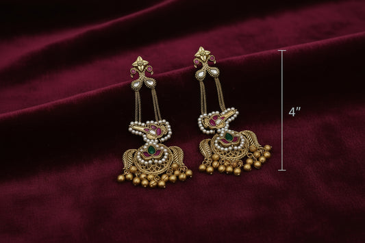 Pair of gold earrings with gemstones on a white round platform