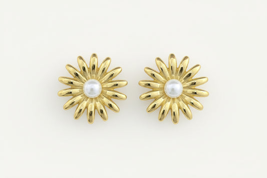 Gold earrings with pearl centers on a white background