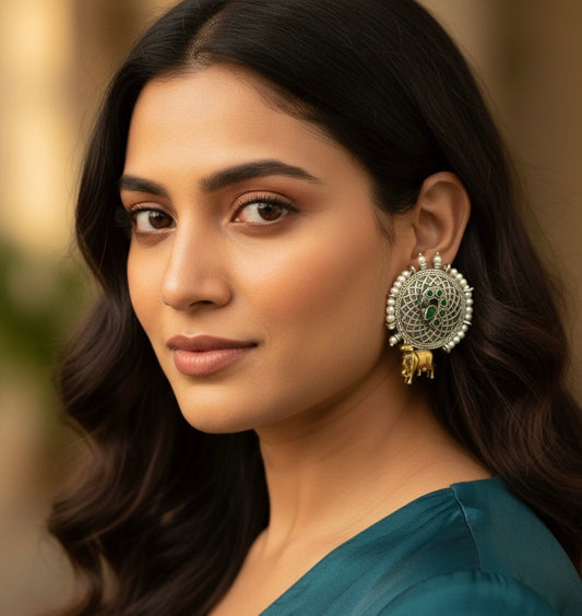 Woman wearing large, ornate earrings with a blurred background