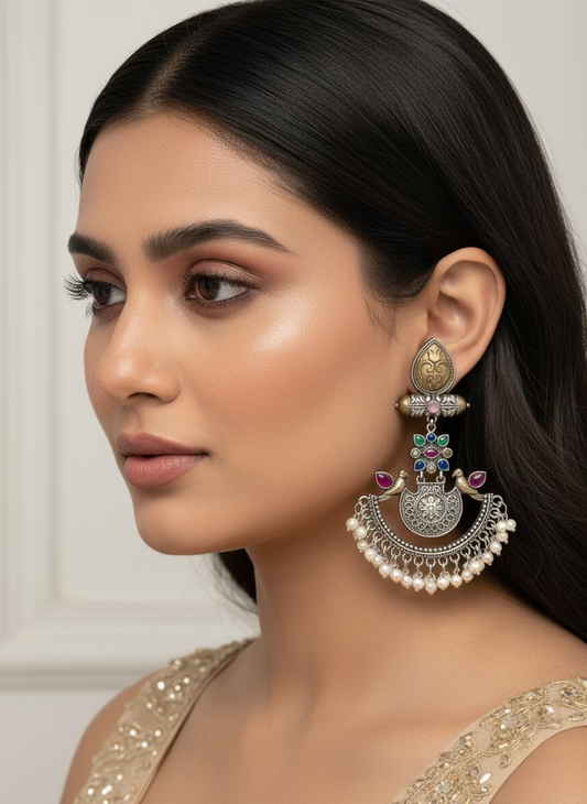 Pair of ornate earrings with decorative elements on a white background