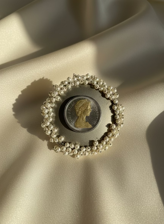 Pearl bracelet with a coin on a beige fabric background
