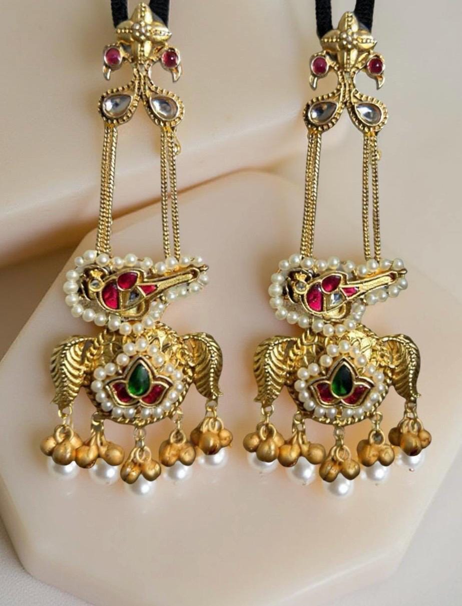 Ornate gold earrings with pearls and gemstones on a light background