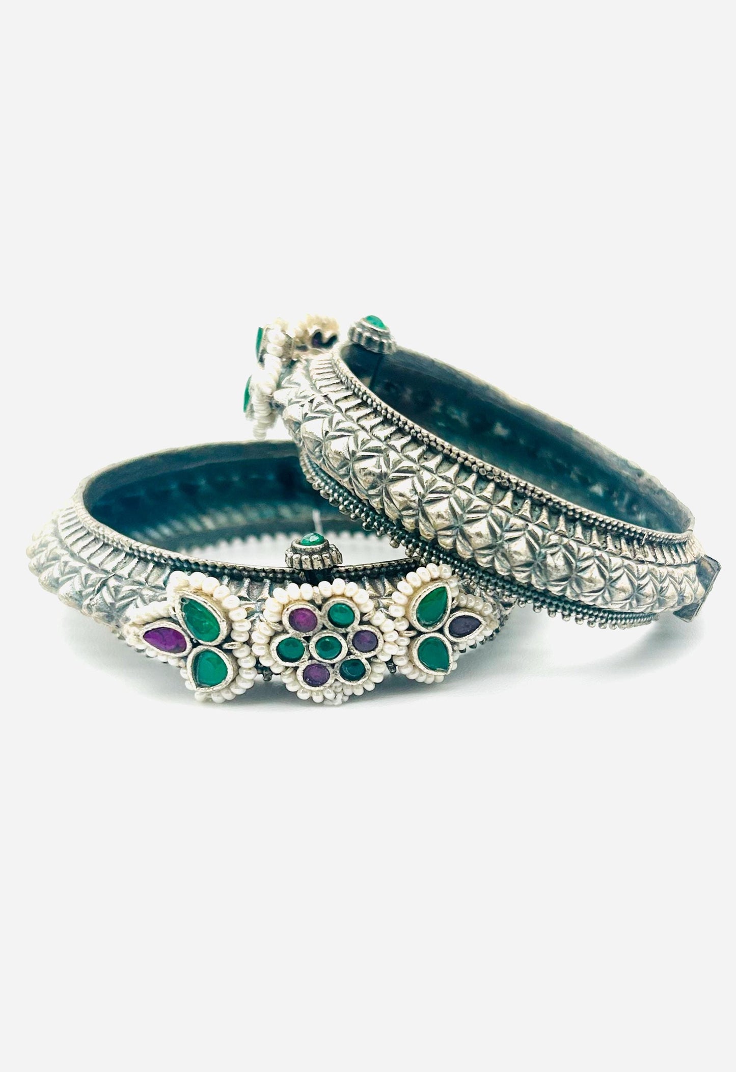Pair of decorative bangles with floral designs on a white background