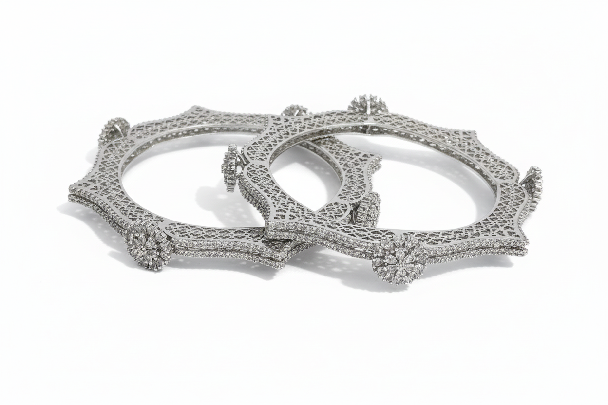Two silver bangles with intricate designs on a white background