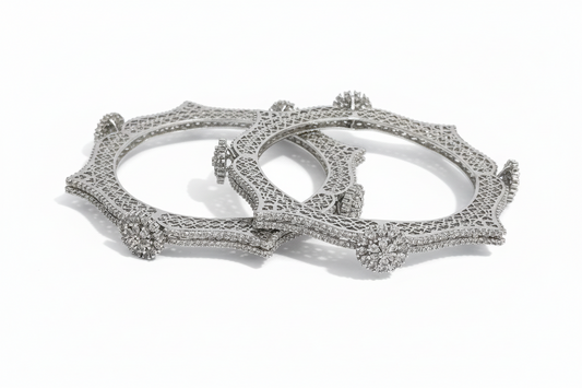 Two silver bangles with intricate designs on a white background