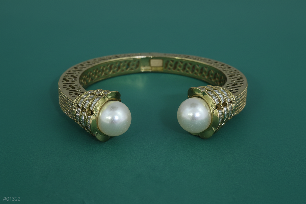 Gold bracelet with pearl-like beads on a teal background