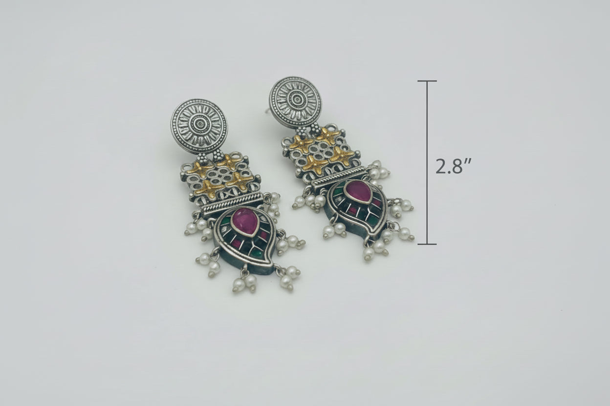 Pair of ornate earrings with mongo leaf-shaped designs on a white background