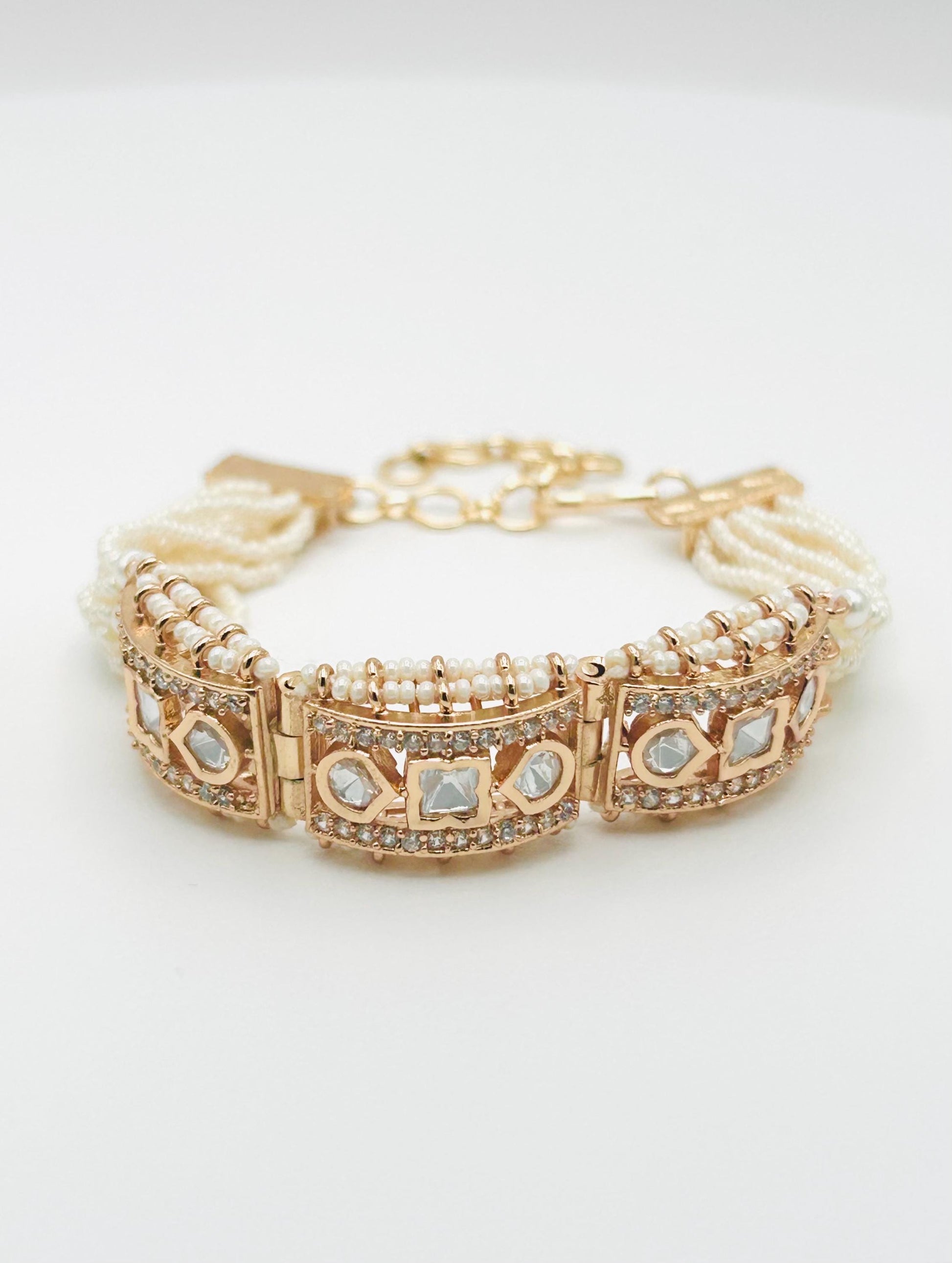 Gold bracelet with pearl and gemstone accents on a light background