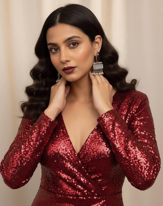 Woman wearing a red sequin dress with earrings against a beige background