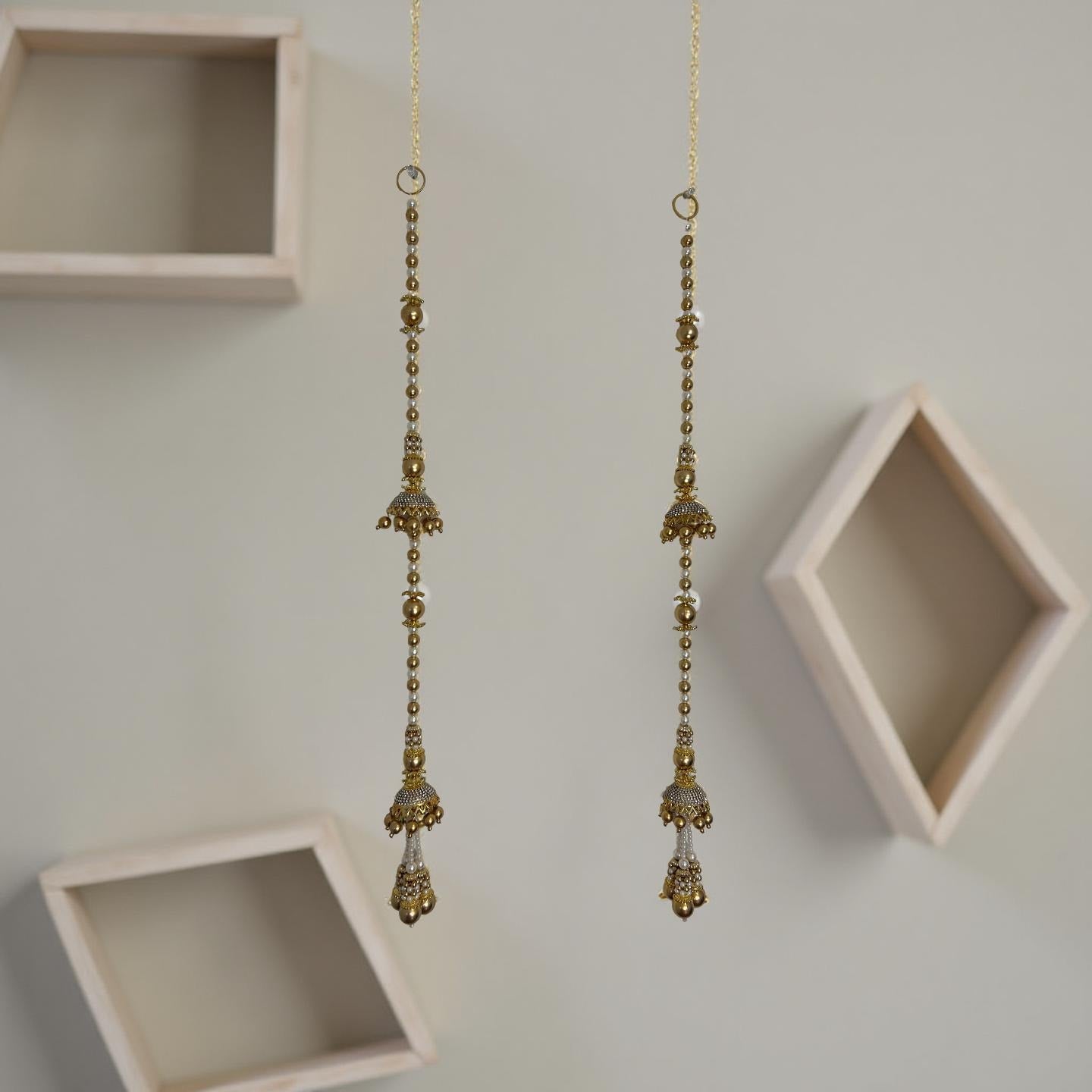 Gold hanging earrings with decorative elements on a light gray background