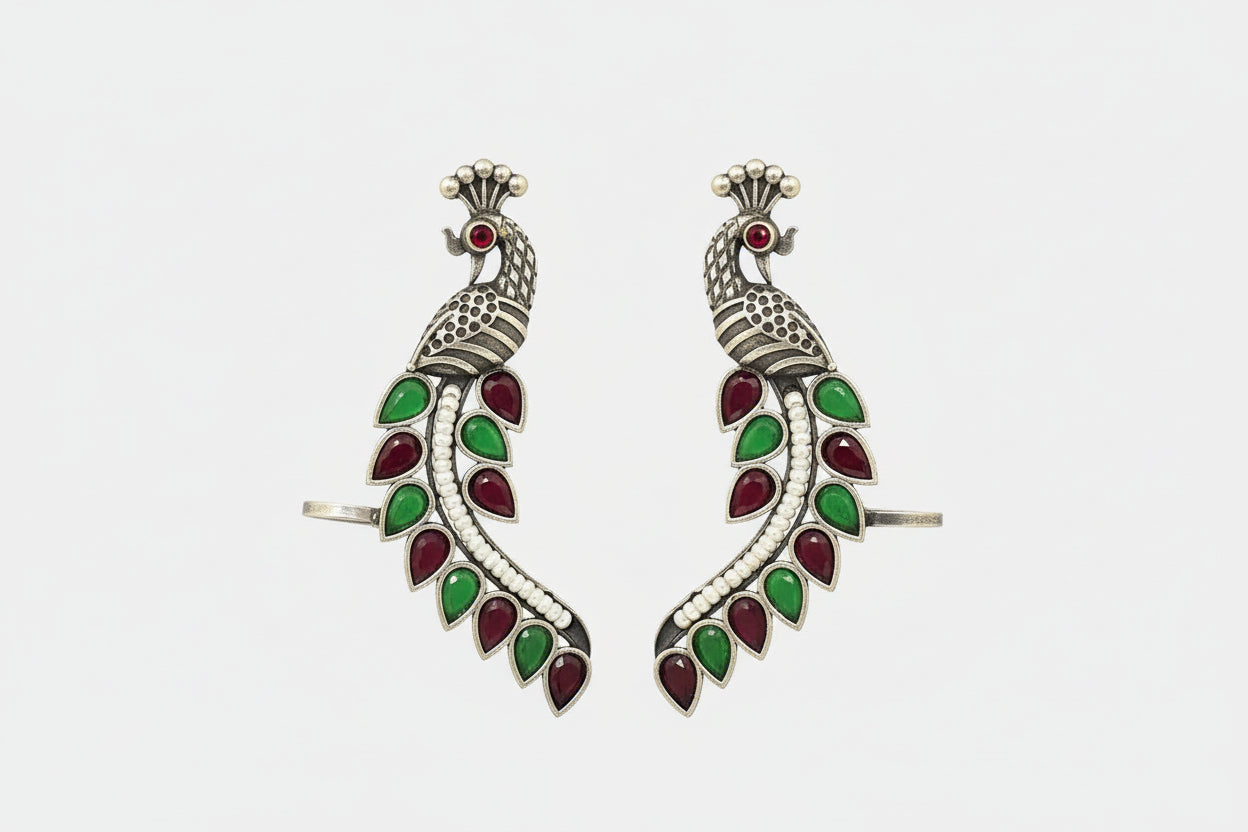 Pair of silver earrings with green and red gemstones on a green background