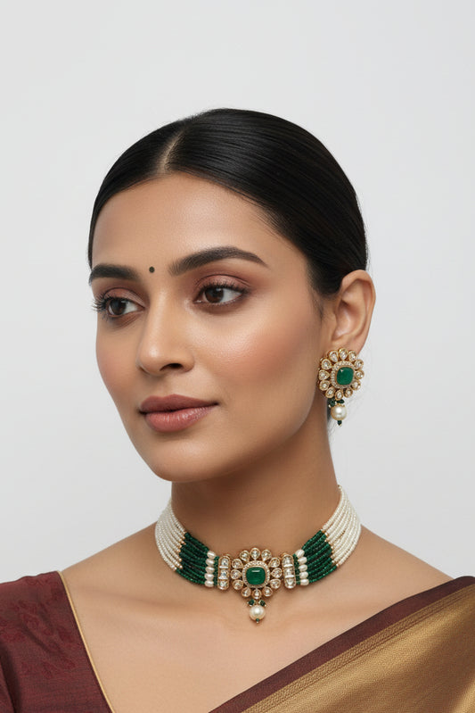 choker necklace and earrings with green and gold accents on a white stand.