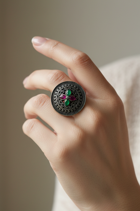 Hand wearing a decorative temple ring with gemstones on a neutral background