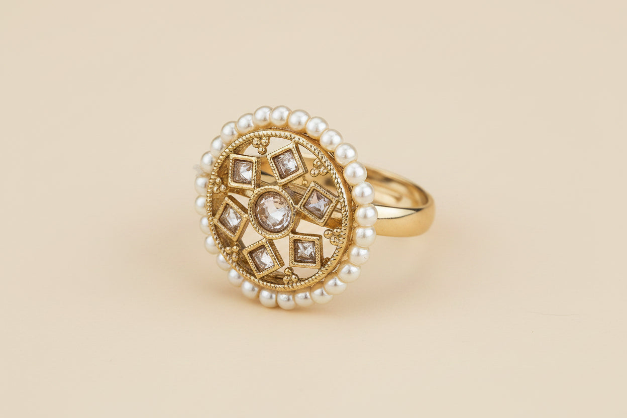 traditional charm antique Gold plated ring with pearl and clear white diamond accents on a beige background 