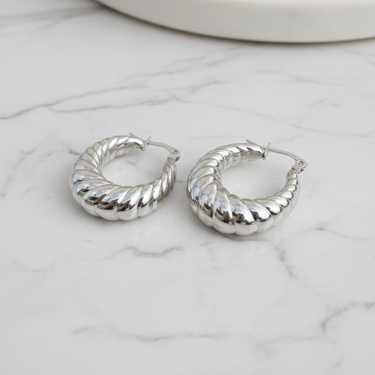 Silver hoop earrings on a marble surface