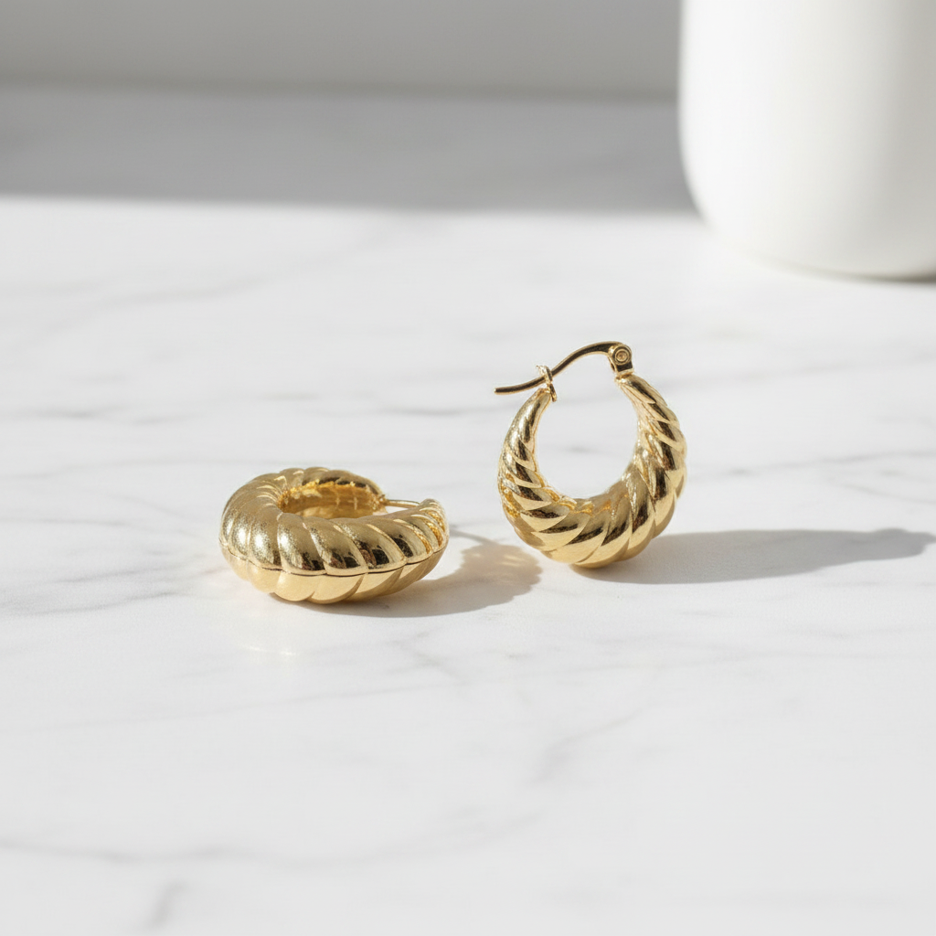 Gold hoop earrings on a light surface with a white background