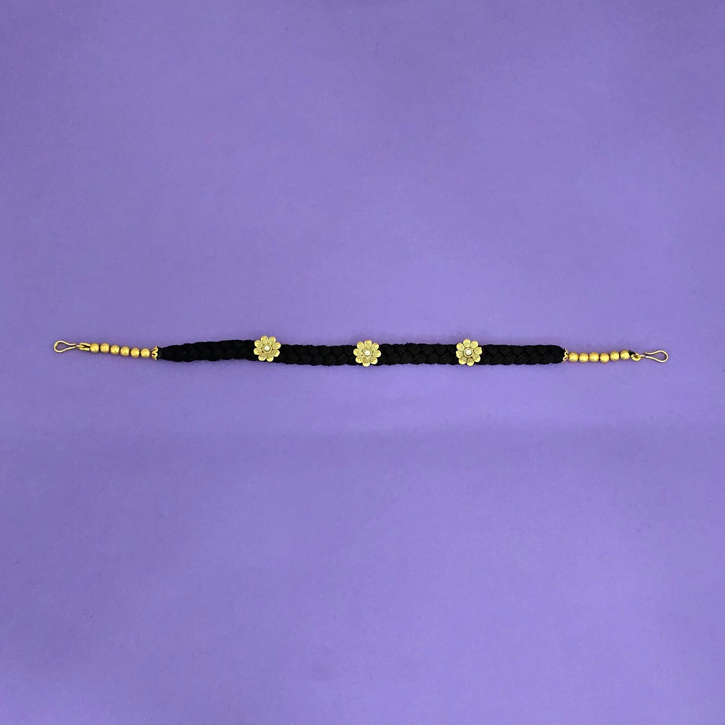 Black and gold hair band with floral designs on a purple background