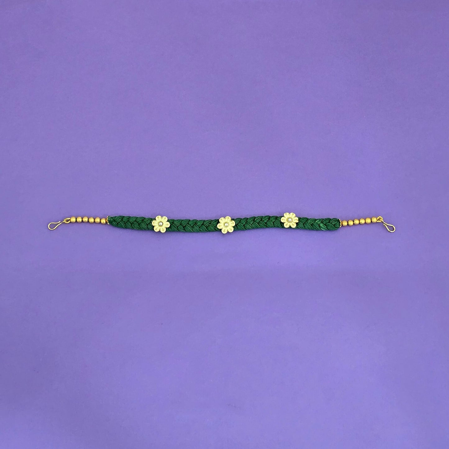 Green braided shishphool  with gold flowers and beads on a purple background
