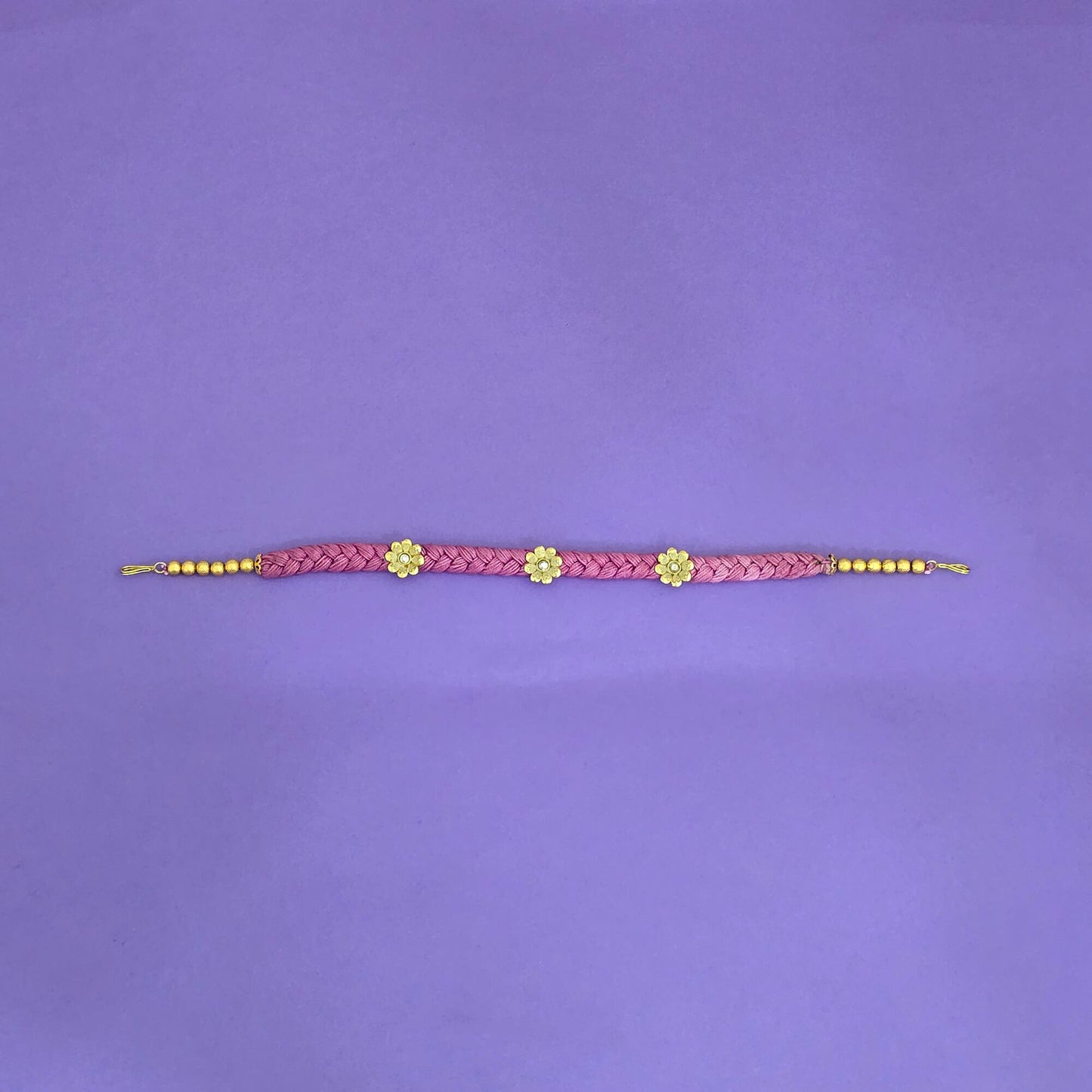 hair band with pink braided design and gold accents on a purple background