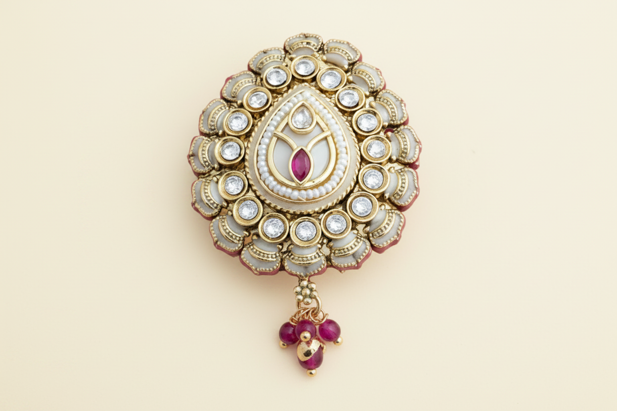 Decorative safety pin brooch with gold, pearl, and red  white gemstone details on a white background
