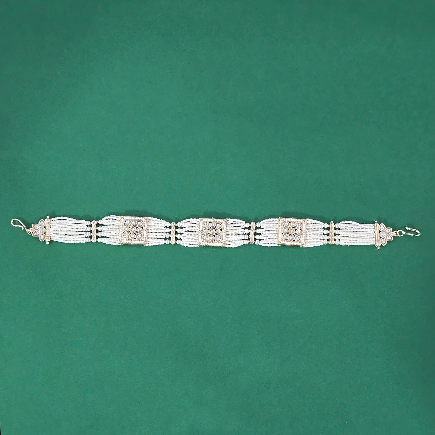 gold plated multi layered pearl hair tassels with decorative clear ad elements on a green background