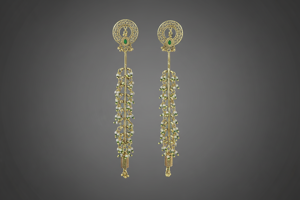 Pair of antique gold plated long kashmiri earrings with green gemstones on a black background