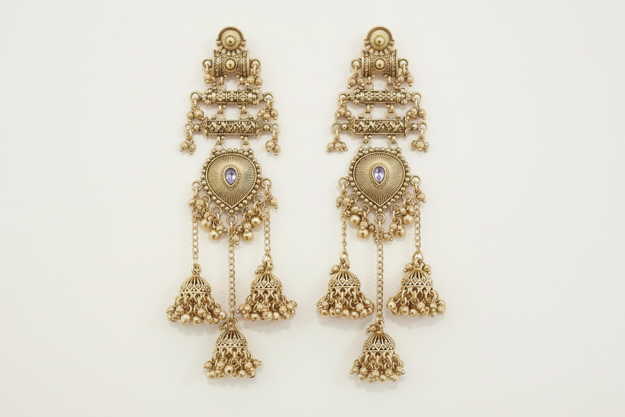 Pair of gold earrings with intricate designs on a light beige background