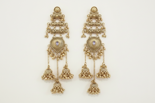 Pair of gold earrings with intricate designs on a light beige background