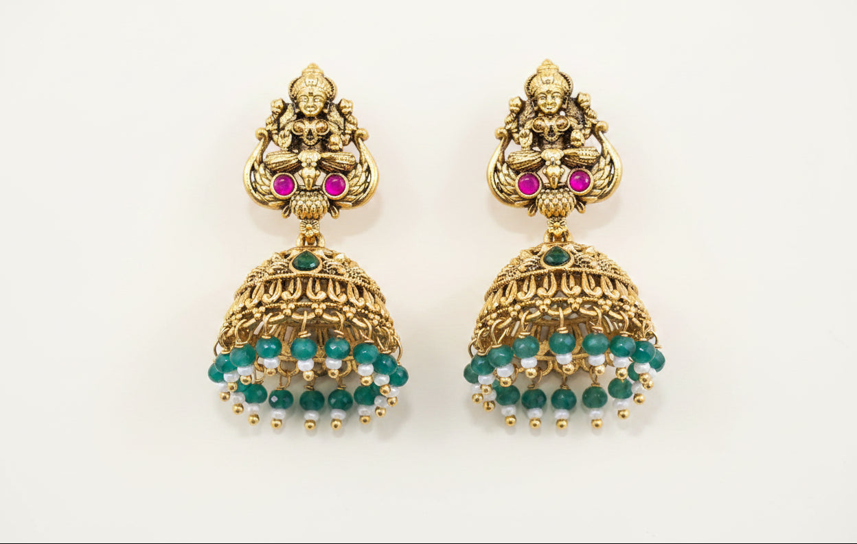 temple antique gold plated earrings with gemstones on a green background
