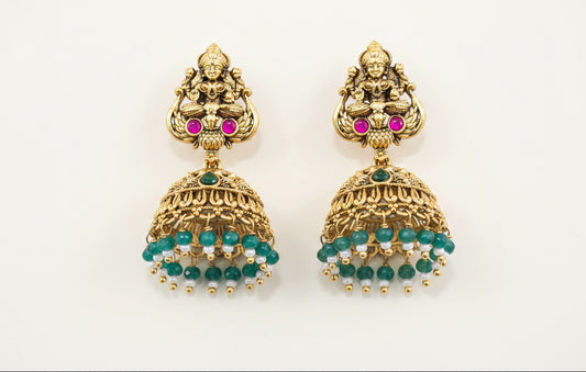 temple antique gold plated earrings with gemstones on a green background