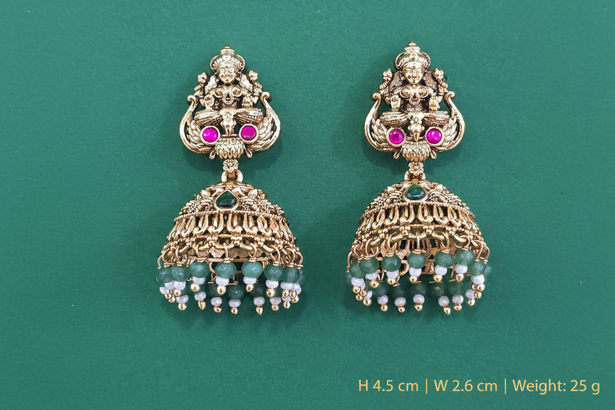 occasionally wearing temple antique gold plated earrings with gemstones on a green background
