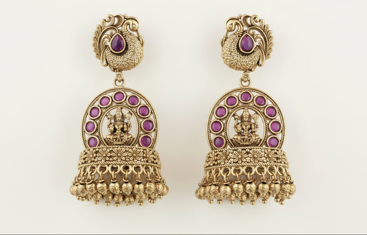 Ornate gold earrings with ruby red  gemstones on a green background