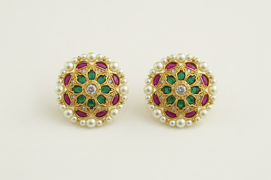 Pair of gold earrings with green and red gemstones on a white background