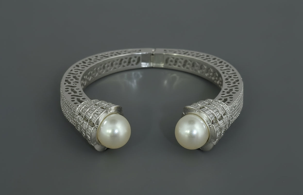 Silver kada with pearl-like beads on a red background
